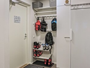 Un placard de rangement avec des étagères où sont rangés des sacs et des chaussures.