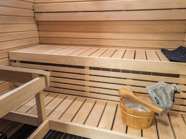 Un sauna en bois avec des bancs, un seau en bois et une serviette.