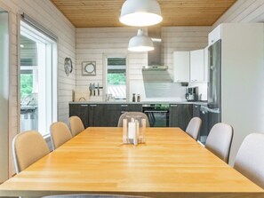 A modern kitchen with wooden cabinets, a large island, and a dining area with chairs.