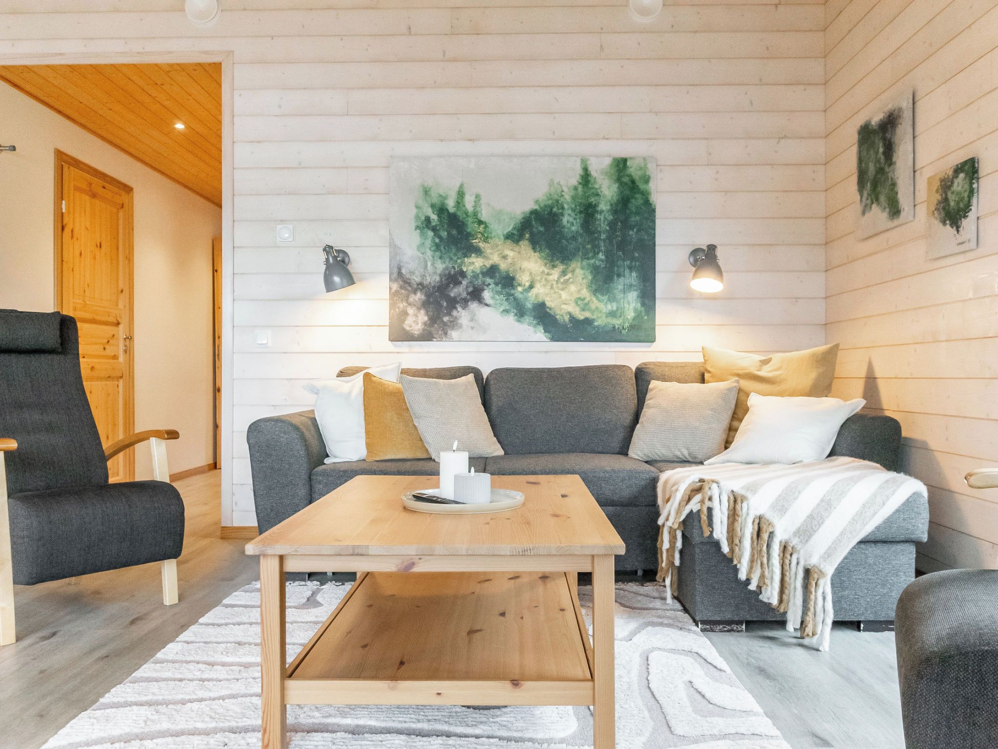 A cozy living room with a wooden coffee table, grey sofa, and a large abstract painting on the wall.