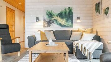 A cozy living room with a wooden coffee table, grey sofa, and a large abstract painting on the wall.