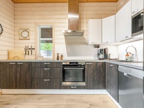 A modern kitchen with wooden cabinets, a built-in oven, and a dishwasher. - Kalliolaakso by Interhome (Ikaalinen)