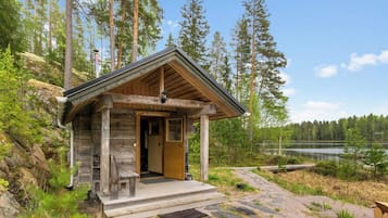 A wooden cabin with a porch, a door, and a small window.