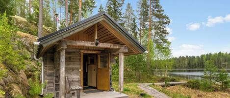 Eine Holzhütte mit Veranda, Tür und kleinem Fenster.