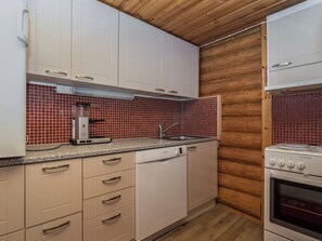 Une cuisine compacte avec des meubles blancs, un crédence carrelé de couleur rouge, un lave-vaisselle et un four Electrolux.