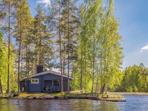 A cabin by a lake surrounded by tall trees. - Aurinkoniemi by Interhome (Mikkeli)