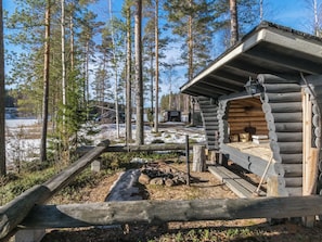 A log cabin with a metal roof, surrounded by a wooden fence, and a small outdoor fire pit. - Aurinkoniemi by Interhome (Mikkeli)