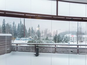 A room with a view of a snowy landscape, a railing, and a bench.