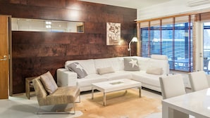 Un salon moderne avec un canapé d’angle, une table basse et un tapis.