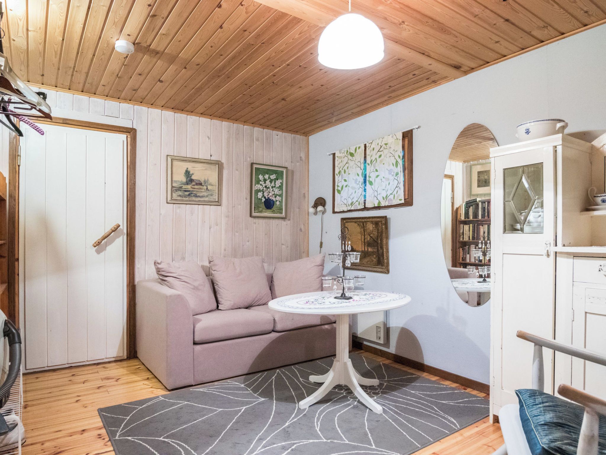 Ein gemütliches Zimmer mit Holzbalkendecke, einem Sofa, einem runden Tisch und einem Schrank.