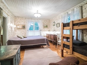 Une chambre avec deux lits simples, un bureau et un lit superposé.