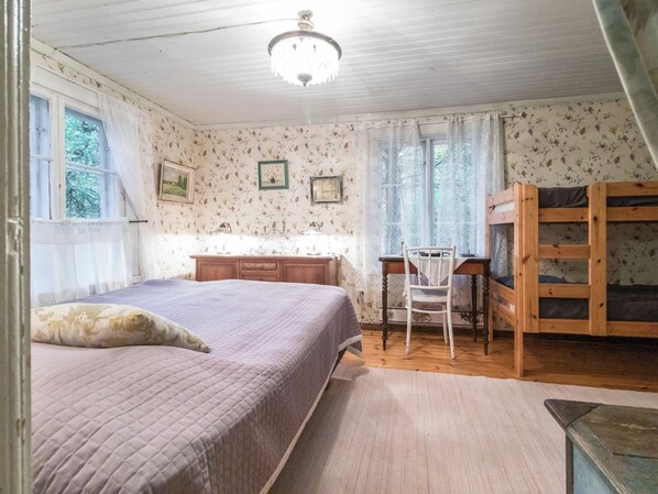 A bedroom with a bed, a desk, a chair, a wardrobe, and a window with curtains.