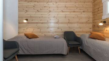 Una habitación pequeña y acogedora con dos camas, una silla y una lámpara en la pared.