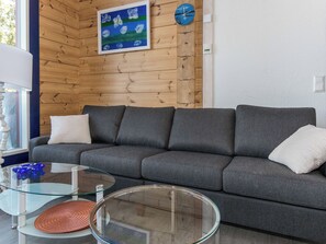 A modern living room with a grey sofa, glass coffee table, and a painting on the wall. - Klippan by Interhome (Ruovesi)