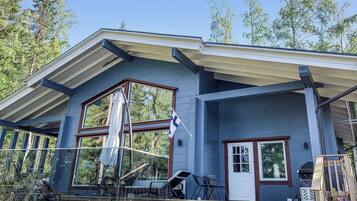 A modern house with a large porch, a flag, and a deck.