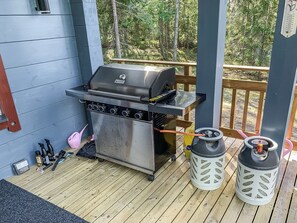 A barbecue grill on a wooden deck with a blue wall and a wooden railing in the background. - Klippan by Interhome (Ruovesi)
