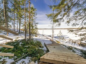 A wooden deck leading through a snowy forest towards a lake. - Klippan by Interhome (Ruovesi)