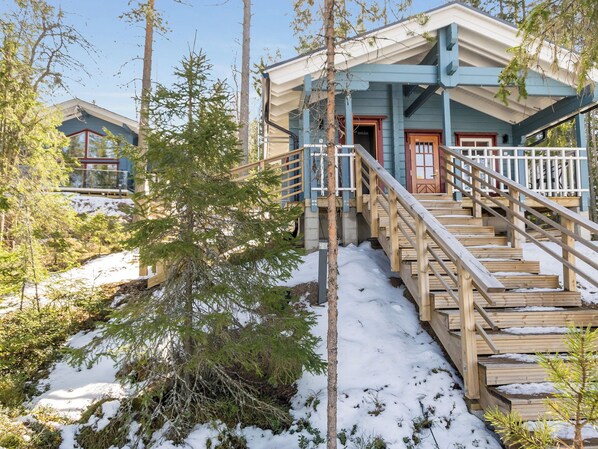 A wooden staircase leading to a building with a blue exterior and a red door. - Klippan by Interhome (Ruovesi)