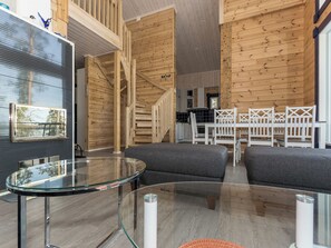 A modern interior with a glass table, grey sofas, wooden walls, and a staircase. - Klippan by Interhome (Ruovesi)