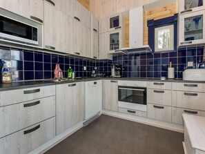 A modern kitchen with wood-paneled cabinets, a built-in oven, and a microwave. - Klippan by Interhome (Ruovesi)