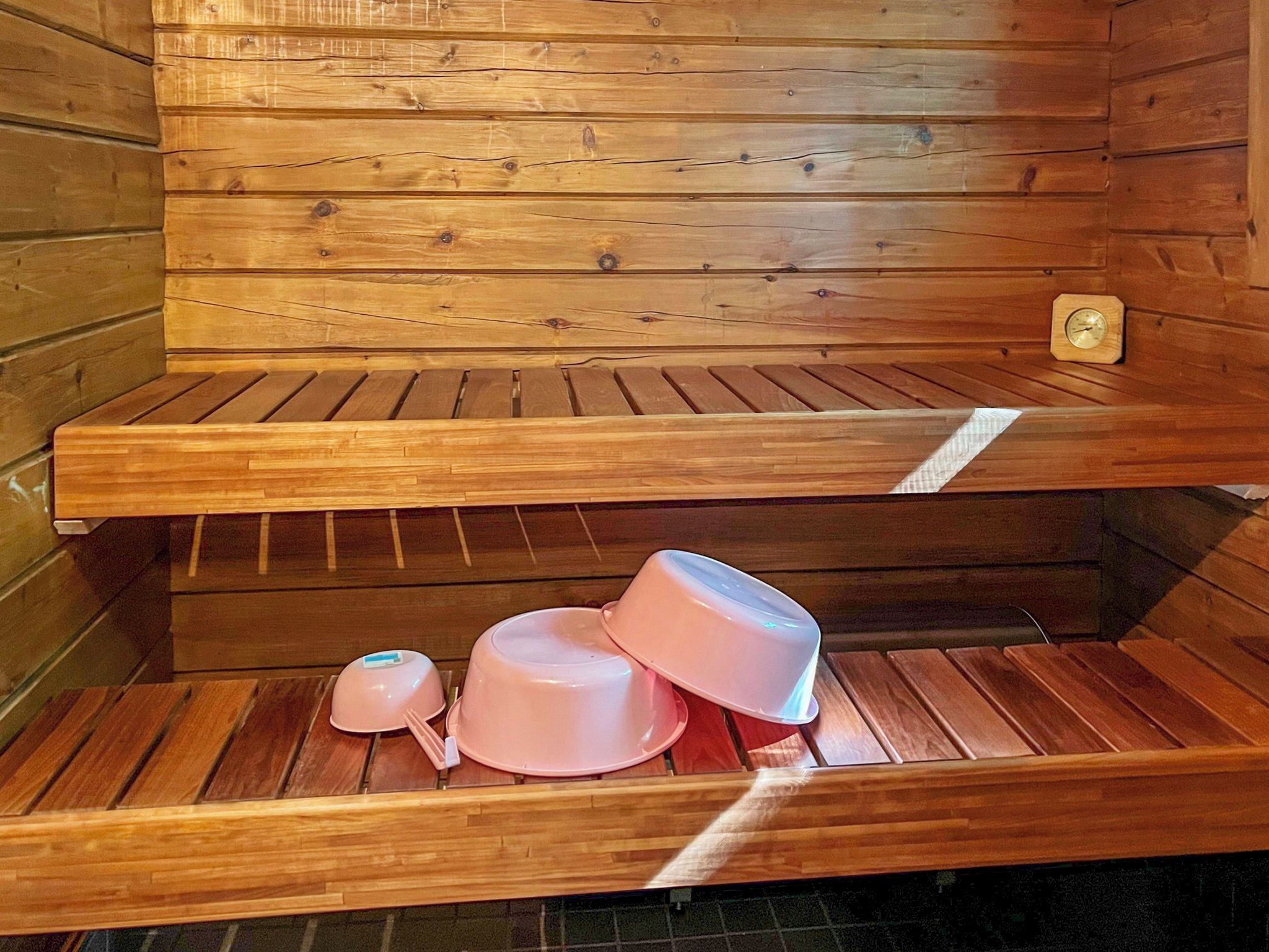Una sauna con bancos de madera y un pequeño reloj en la pared.