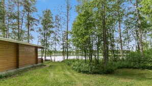 A grassy area with a wooden building, a swing, and a lake in the background.