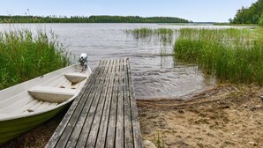 A wooden dock extending into a calm lake with a small boat moored at the end.
