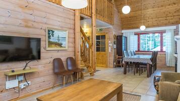 Un interior de madera con televisión, sillas, una mesa y una escalera.