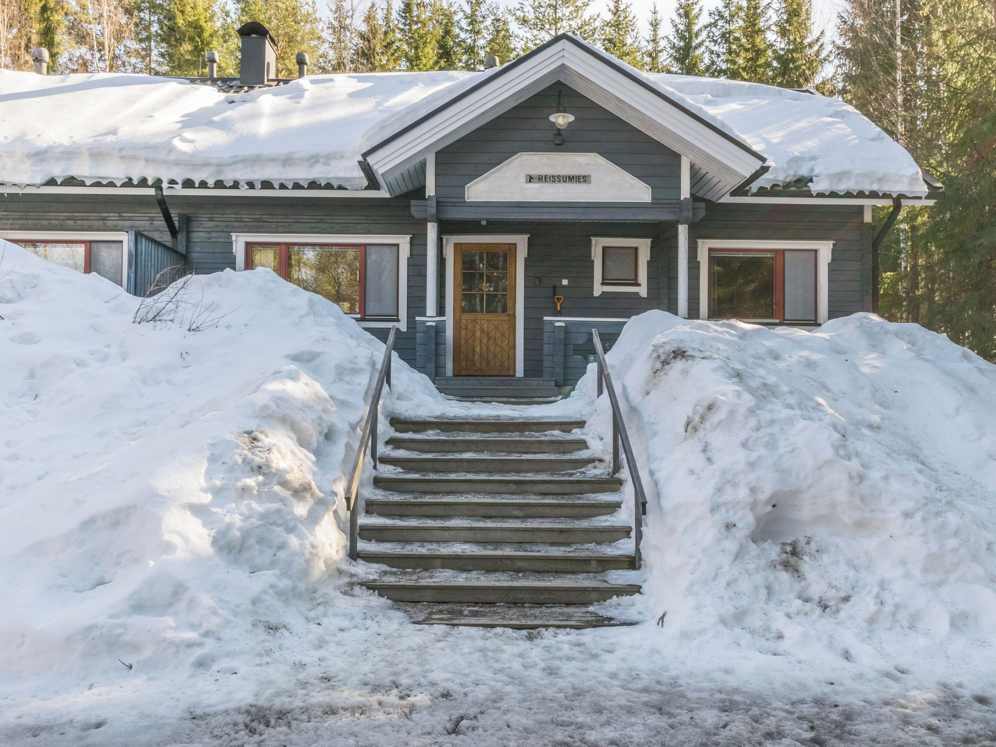 Un edificio de madera con un cartel que dice 'REISSUMIES' en la entrada, rodeado de nieve.