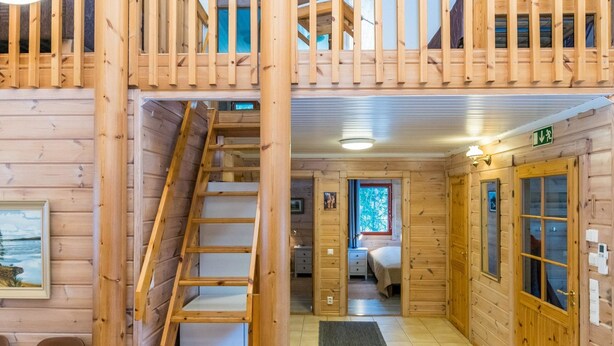 Ein Holzhäuschen im Inneren mit einer Treppe zu einem Schlafzimmer auf dem Dachboden, einem kleinen Badezimmer und einem Essbereich.