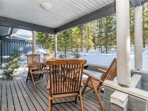 A wooden deck with outdoor seating and a view of a snowy forest.