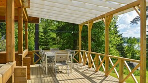 A wooden deck with a table and chairs, surrounded by a wooden railing, overlooking a forested area. - Rinnepelto by Interhome (Nilsiä)