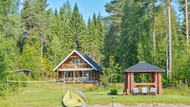 A cabin with a porch and a gazebo by a lake, surrounded by trees. - Rinnepelto by Interhome (Nilsiä)