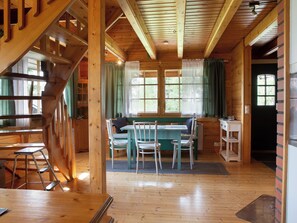 Een houten interieur met een eethoek, een trap en een raam met gordijnen.
