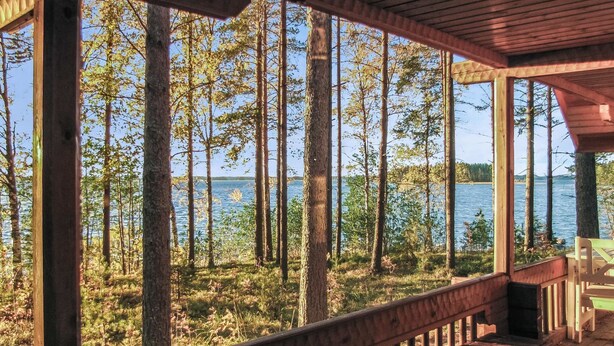 A wooden deck with a view of a forest and a lake. - Auringonlasku by Interhome (Punkaharju)