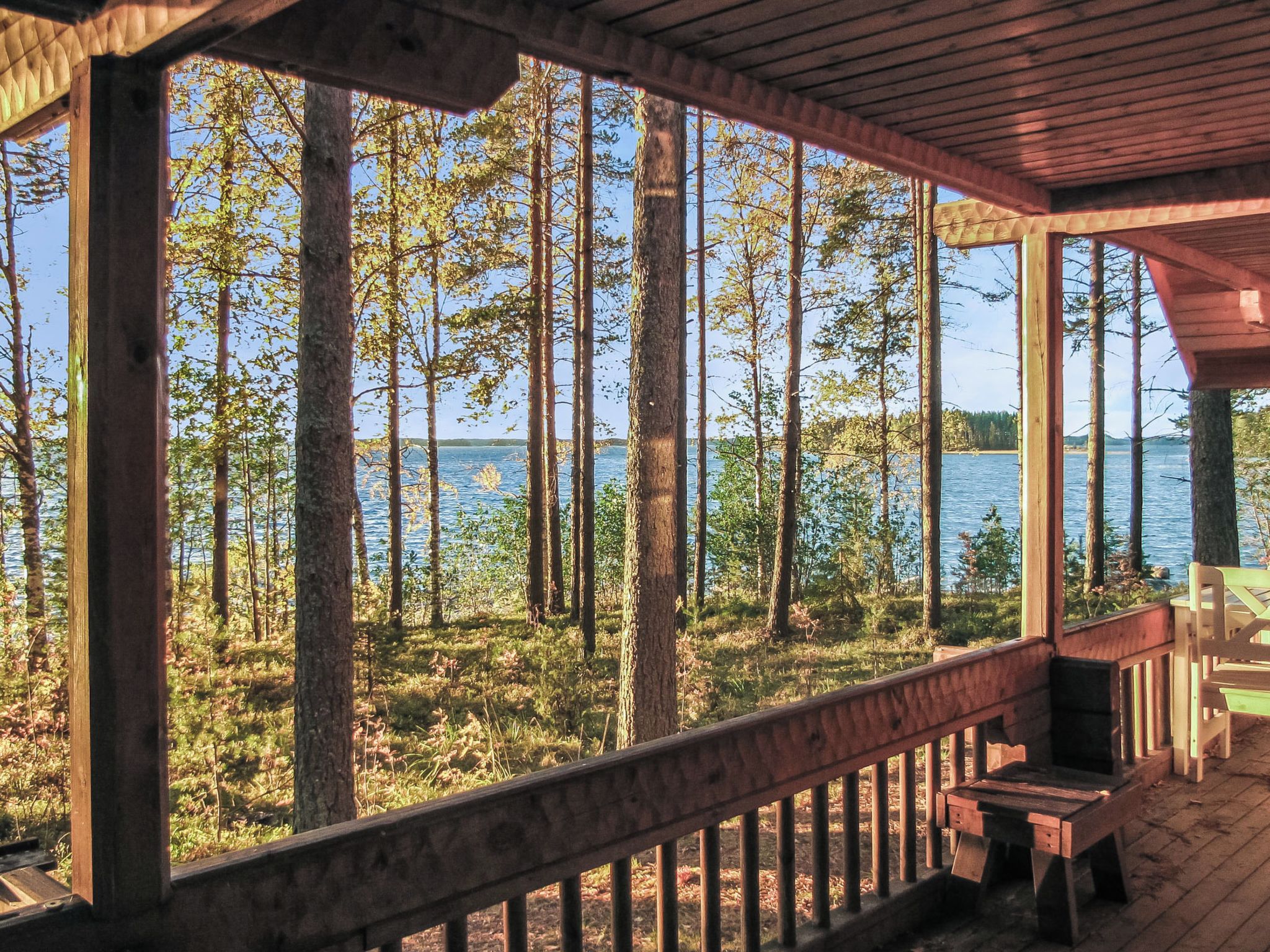 A wooden deck with a view of a forest and a body of water.