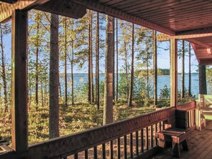 A wooden deck with a view of a forest and a body of water. - Auringonlasku by Interhome (Punkaharju)