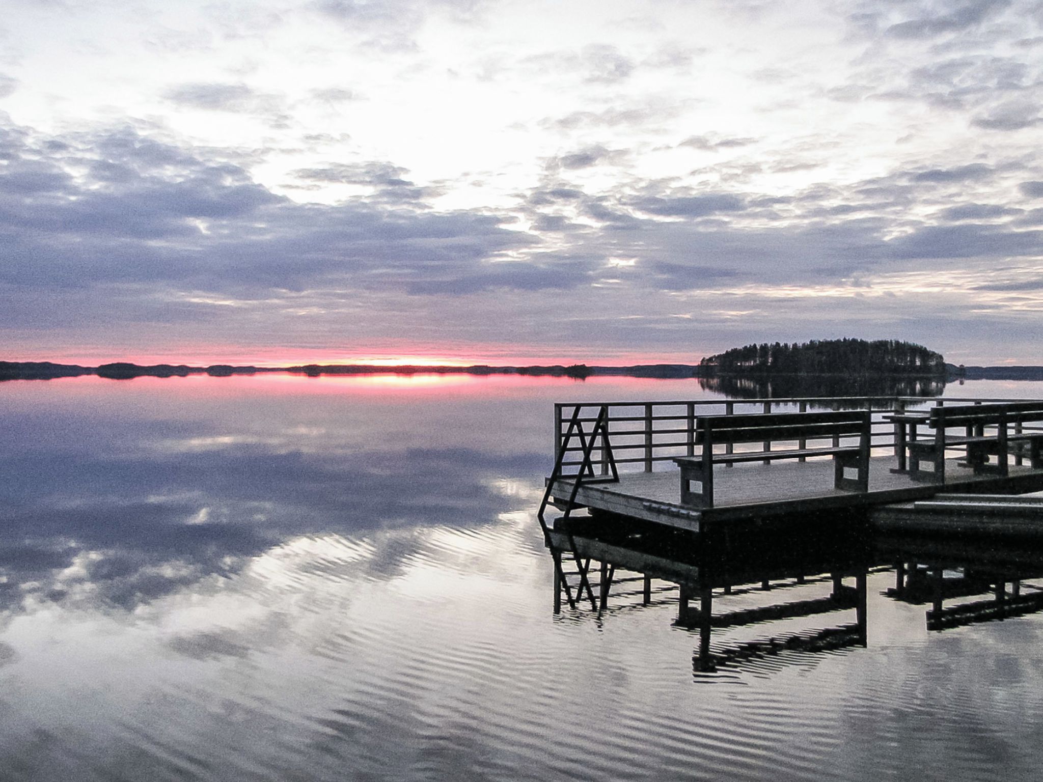 Un lac paisible avec une jetée en bois qui s’avance sur l’eau.