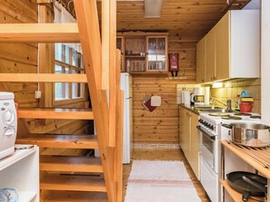 A wooden interior with a kitchen area, including a stove, oven, and a wooden staircase. - Auringonlasku by Interhome (Punkaharju)