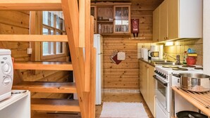 A wooden cabin interior with a kitchen, a dining area, and a staircase. - Auringonlasku by Interhome (Punkaharju)