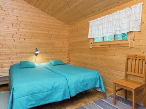 A wooden cabin room with a bed, a chair, and a window with curtains. - Auringonlasku by Interhome (Punkaharju)