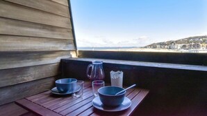 A wooden deck with a table set for two, overlooking a beach and a town. - Les Marinas by Interhome (Deauville-Trouville)