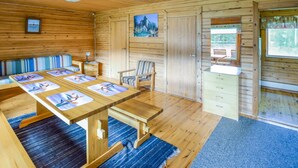 A wooden cabin interior with a dining table, chairs, a bench, a small desk, a chair, a cabinet, and a window. - Sieralahden lomakylä, mökki 1 by Interhome (Savonlinna)