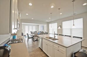 Una cocina moderna con una isla central, muebles blancos y electrodomésticos de acero inoxidable.