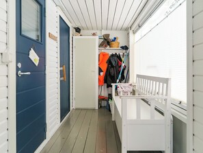 Un pasillo estrecho con una puerta azul que indica 'SAUNA' y un banco blanco.