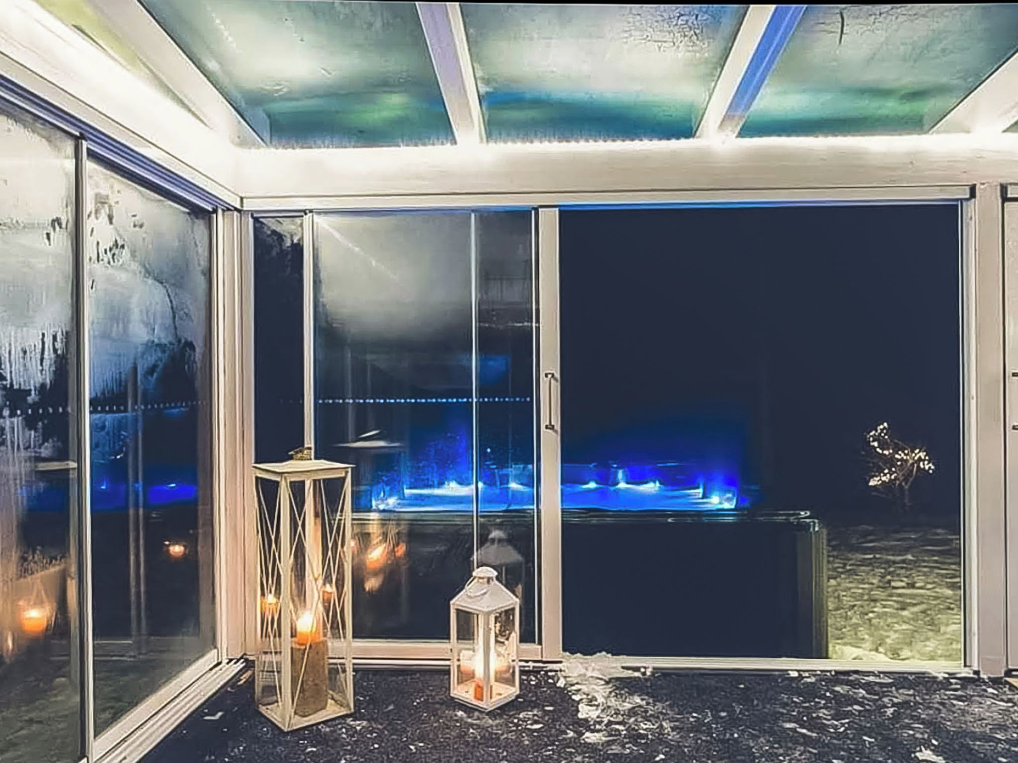 Habitación con amplias puertas de cristal que dan a una zona de piscina, un farol y un techo con una lámpara.