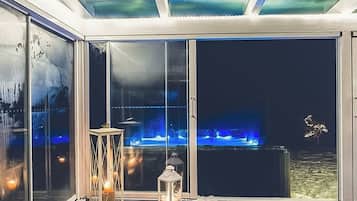 Habitación con amplias puertas de cristal que dan a una zona de piscina, un farol y un techo con una lámpara.