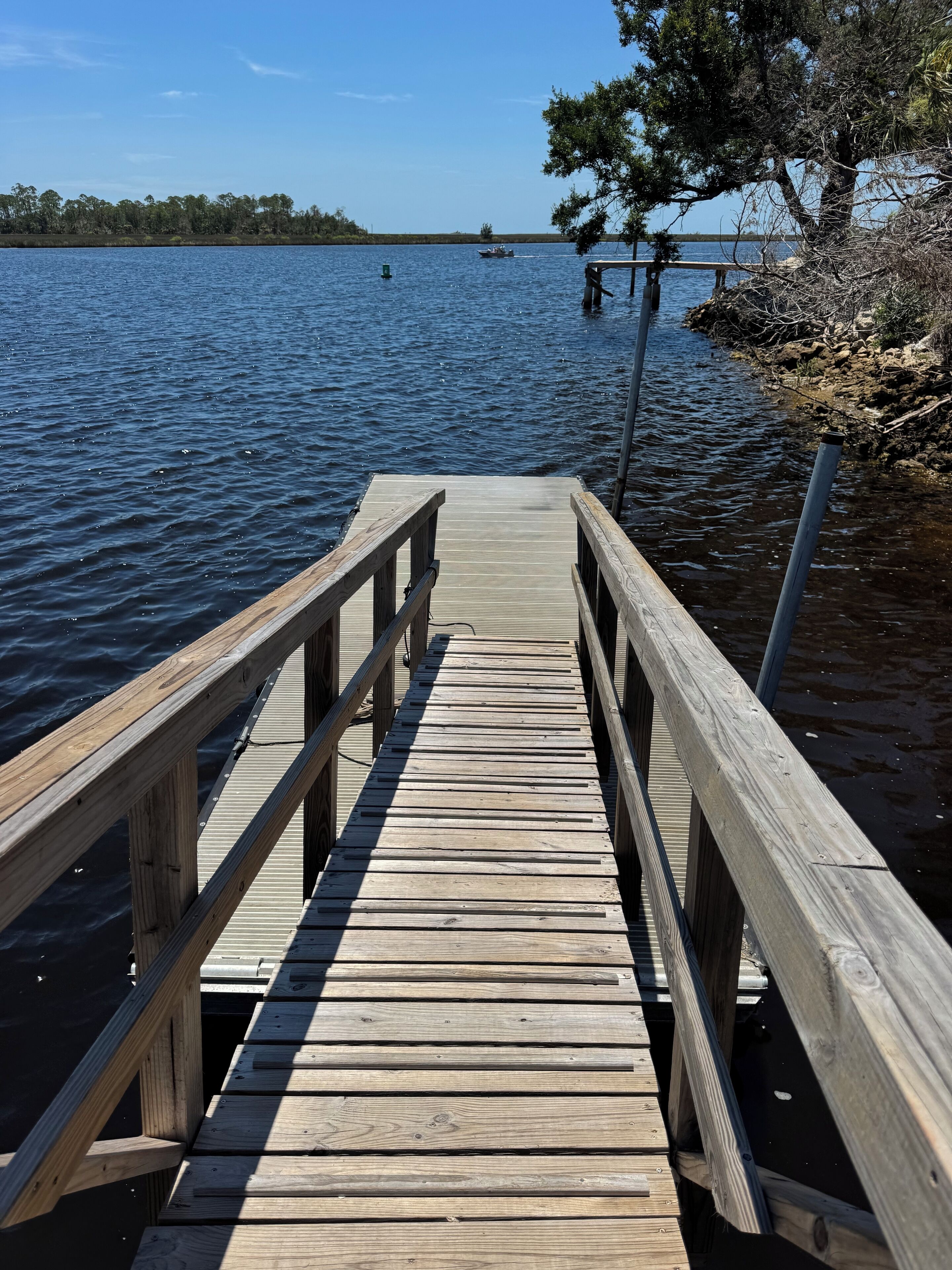 A wooden pier extending into calm water with a clear sky above.