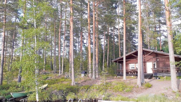 A cabin surrounded by tall trees, a dock, and a small boat. - Aaretti by Interhome (Padasjoki)