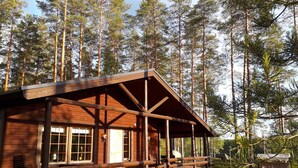 A wooden cabin with a porch, surrounded by tall pine trees. - Aaretti by Interhome (Padasjoki)